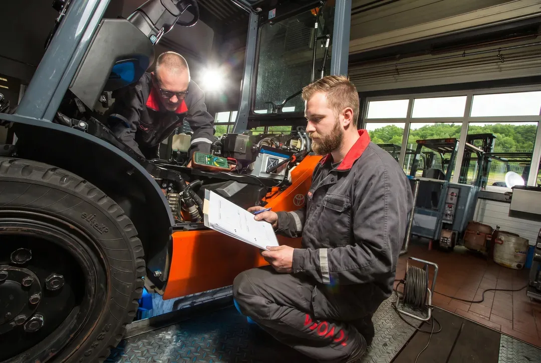 Schaaf-Servicetechniker prüfen einen Toyota-Stapler in der Werkstatt und dokumentieren die Messwerte